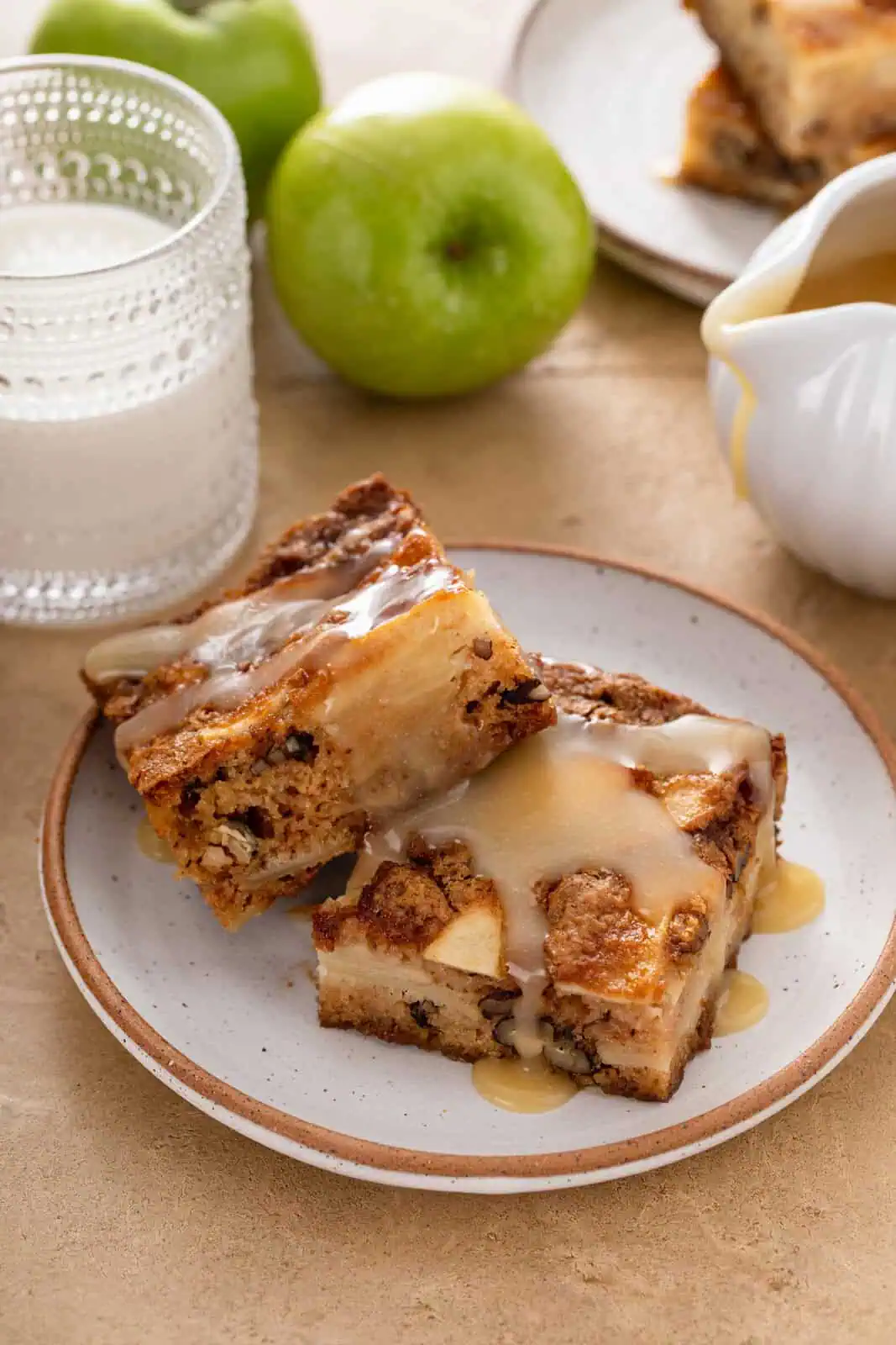 Two slices of apple cake arranged on a plate and topped with dessert sauce.