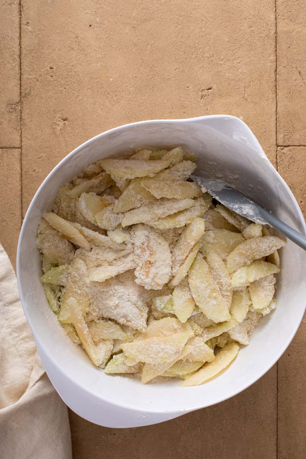Dry ingredients mixed with sliced apples in a white bowl.
