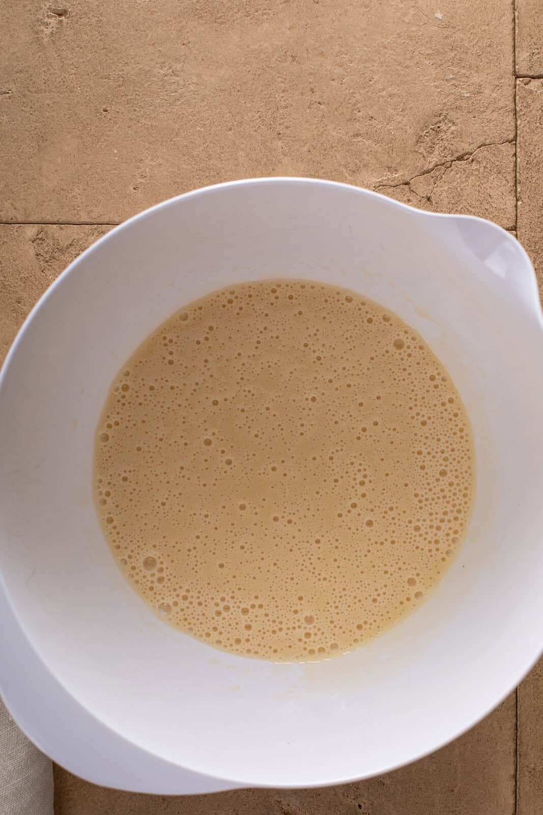 Wet ingredients for apple cake whisked together in a white bowl.