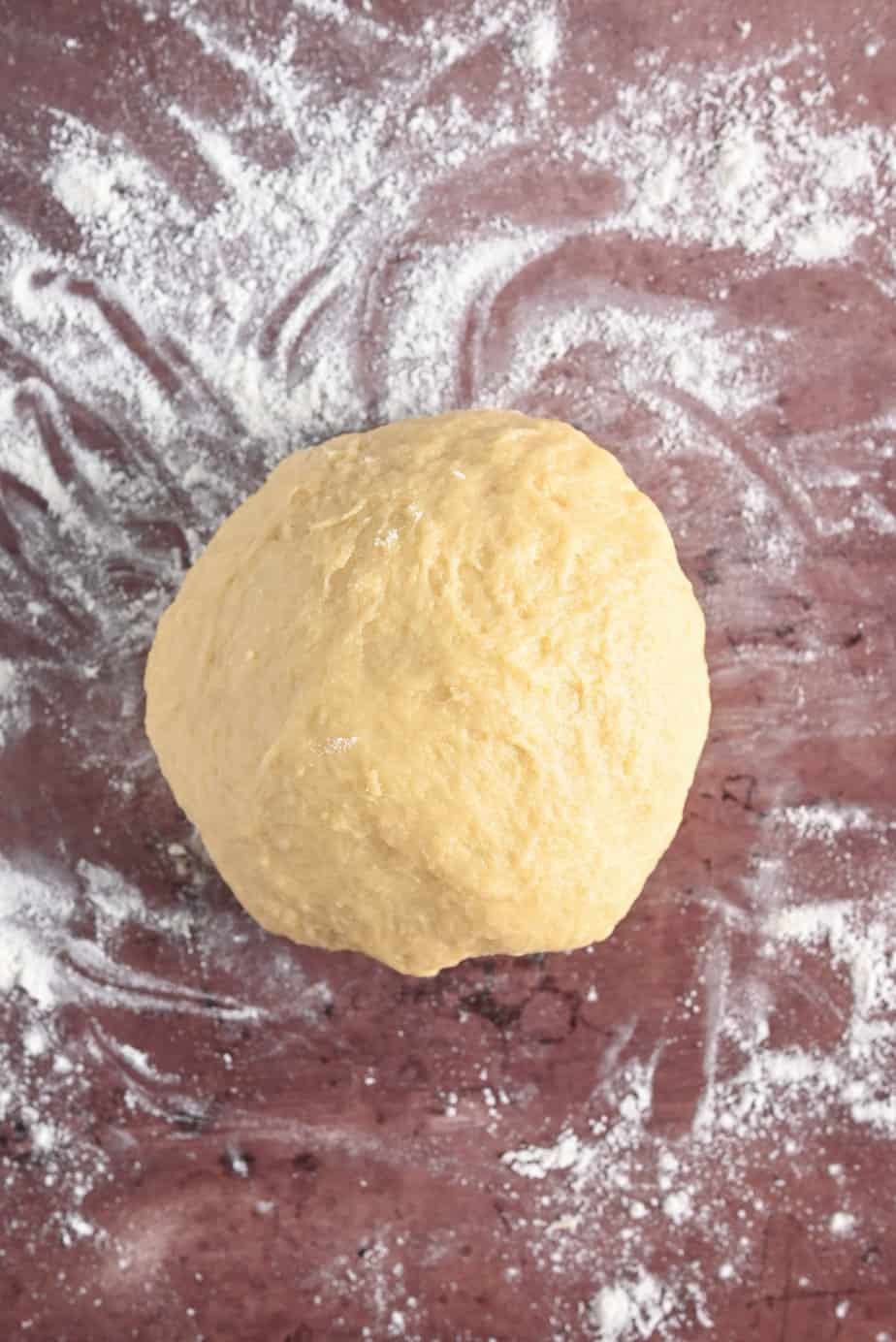 Kneaded dough for pan de muerto on a floured surface.