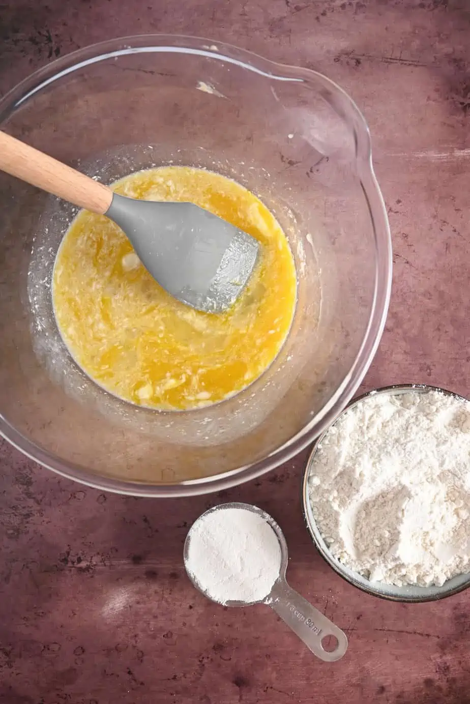 Wet ingredients for pan de muerto in a glass bowl next to the flour.