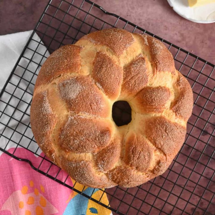Overhead view of pan de muerto cooling on a wire rack.