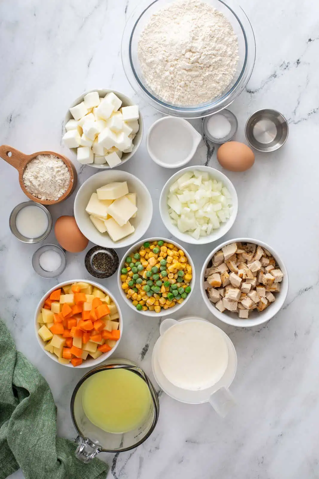 homemade chicken pot pie ingredients arranged on a marble countertop.