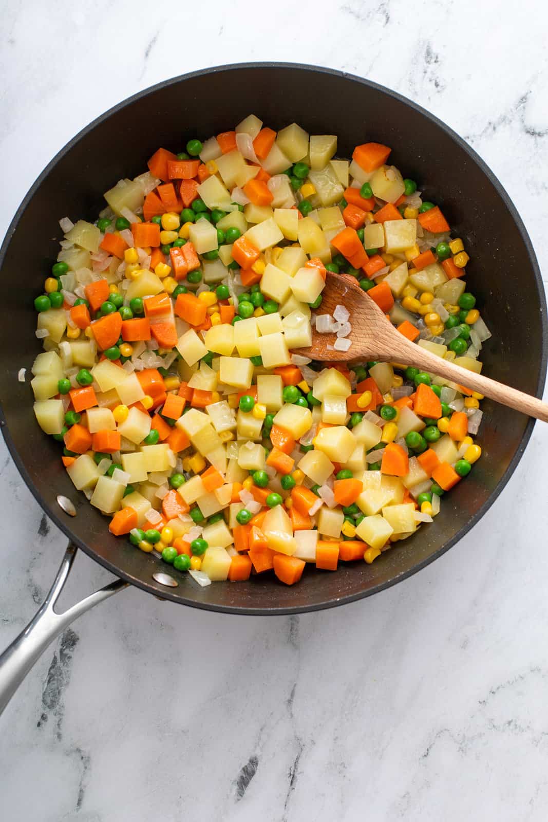 Cooked mixed vegetables in a black skillet.