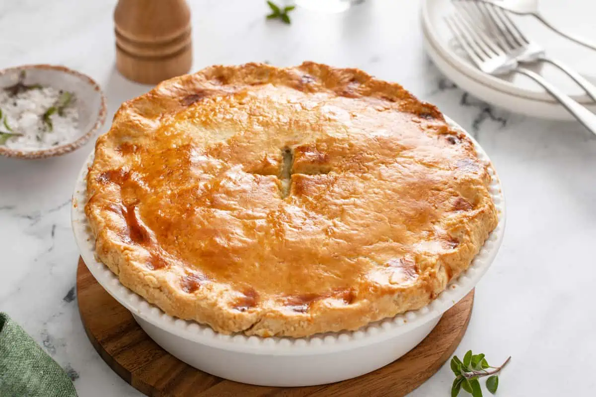 Homemade chicken pot pie rest on a wooden trivet.