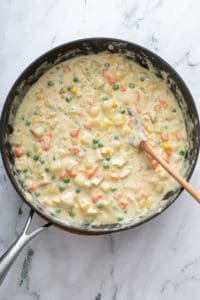 Chicken pot pie filling in a black skillet.