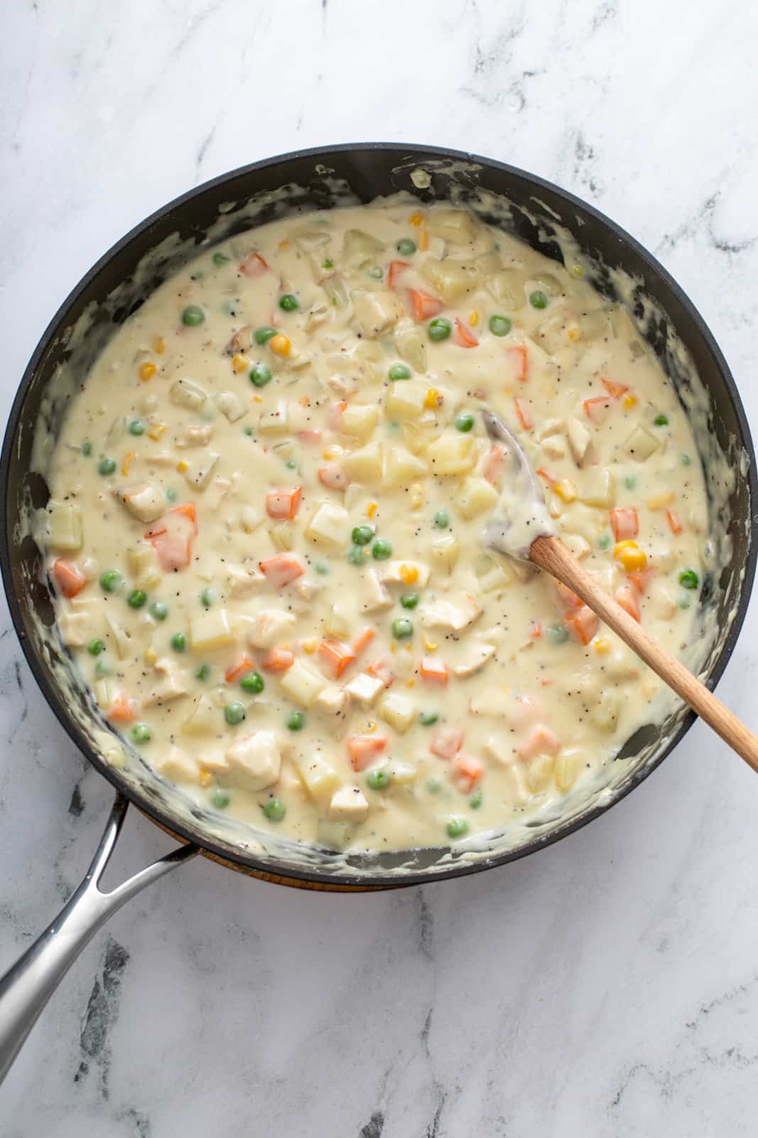 Chicken pot pie filling in a black skillet.