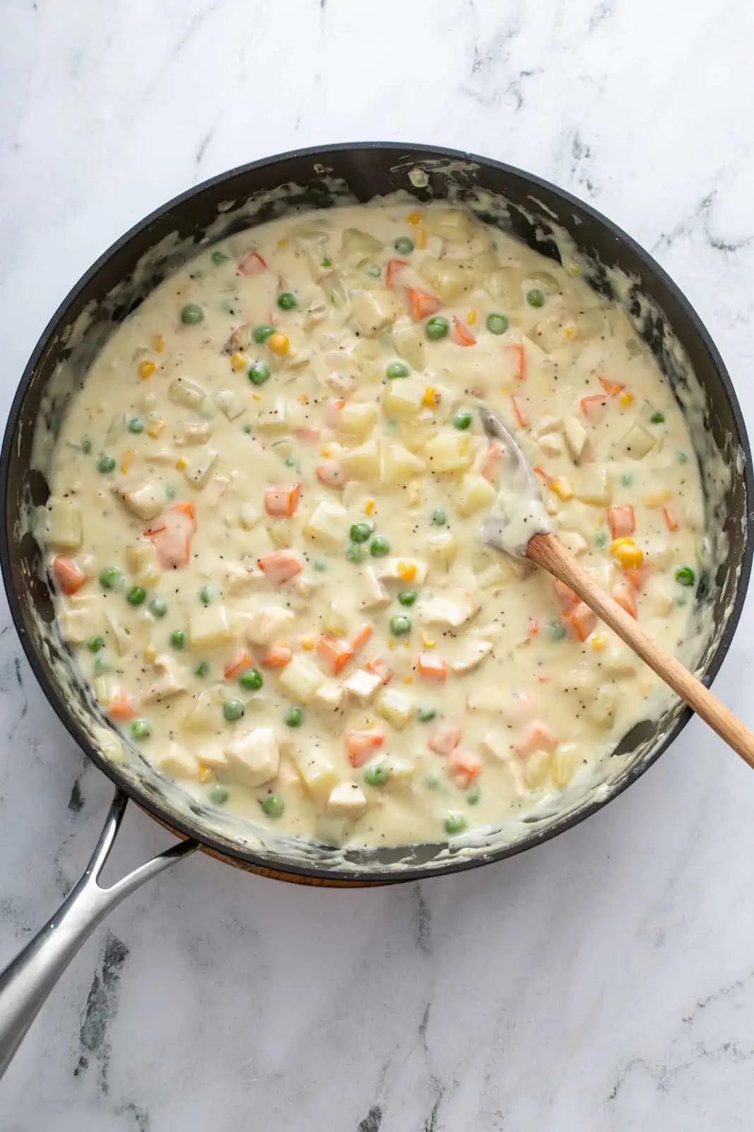 Chicken pot pie filling in a black skillet.