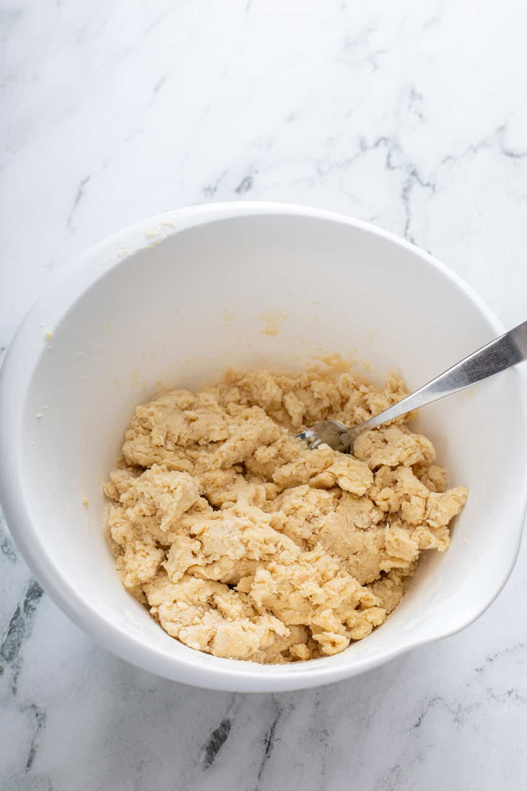 Shaggy pie dough in a white mixing bowl.