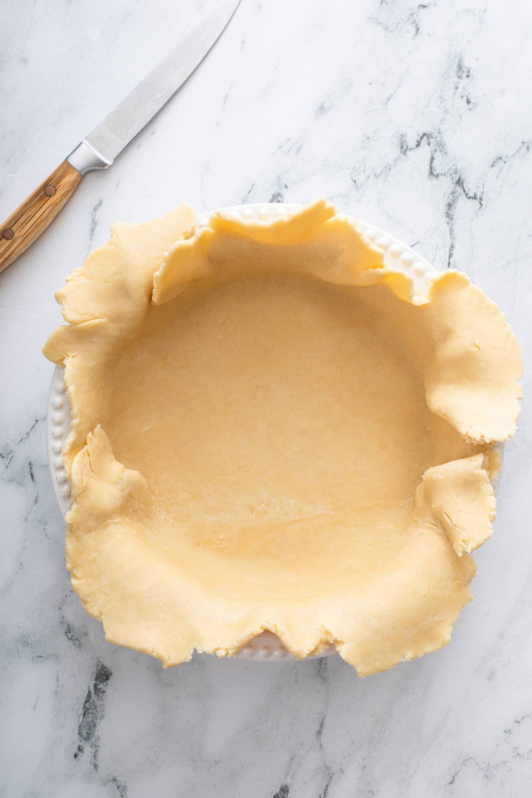 Pie crust lining the bottom of a deep-dish pie plate.