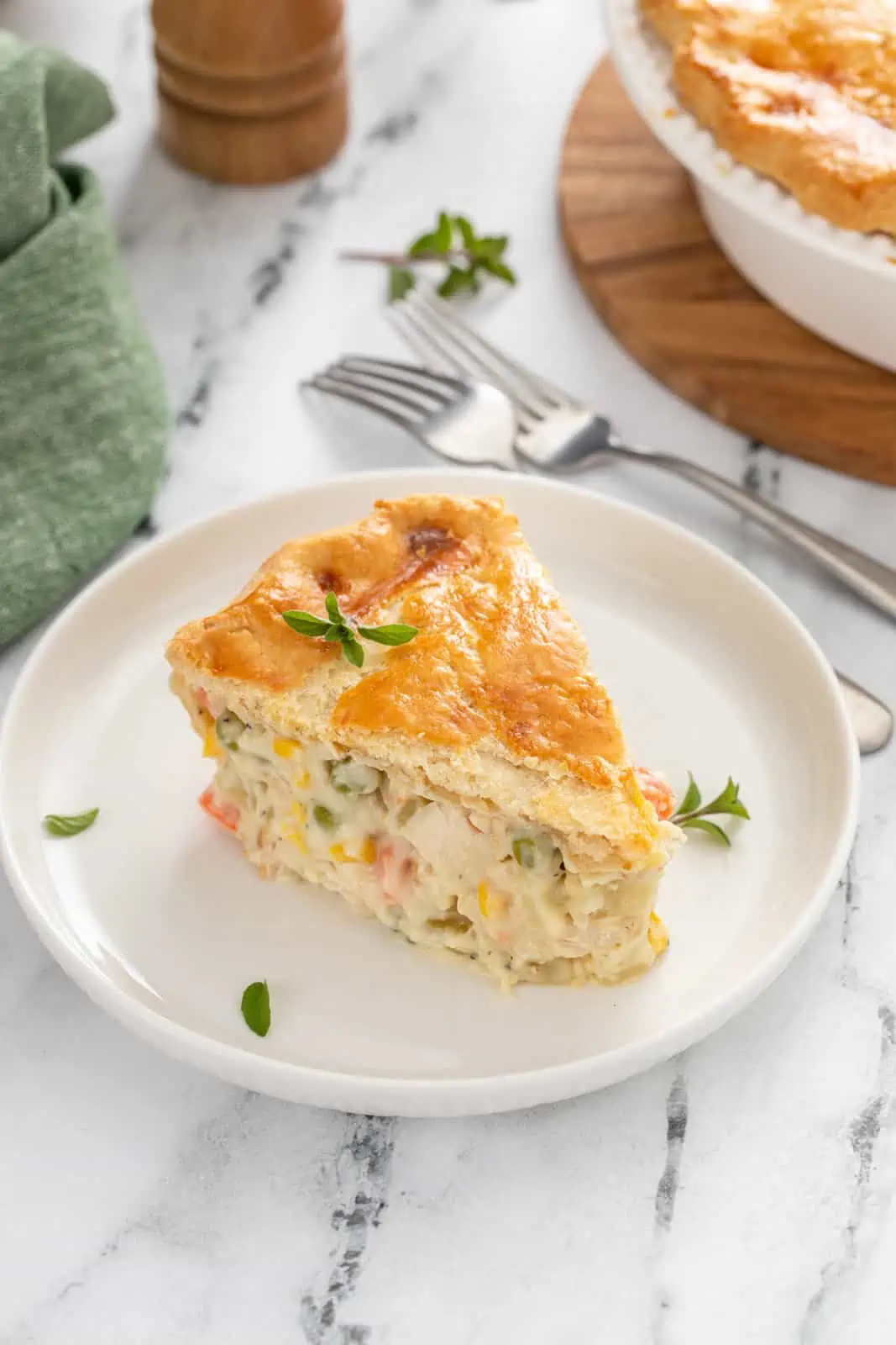 White plate holding a slice of chicken pot pie on a marble surface.