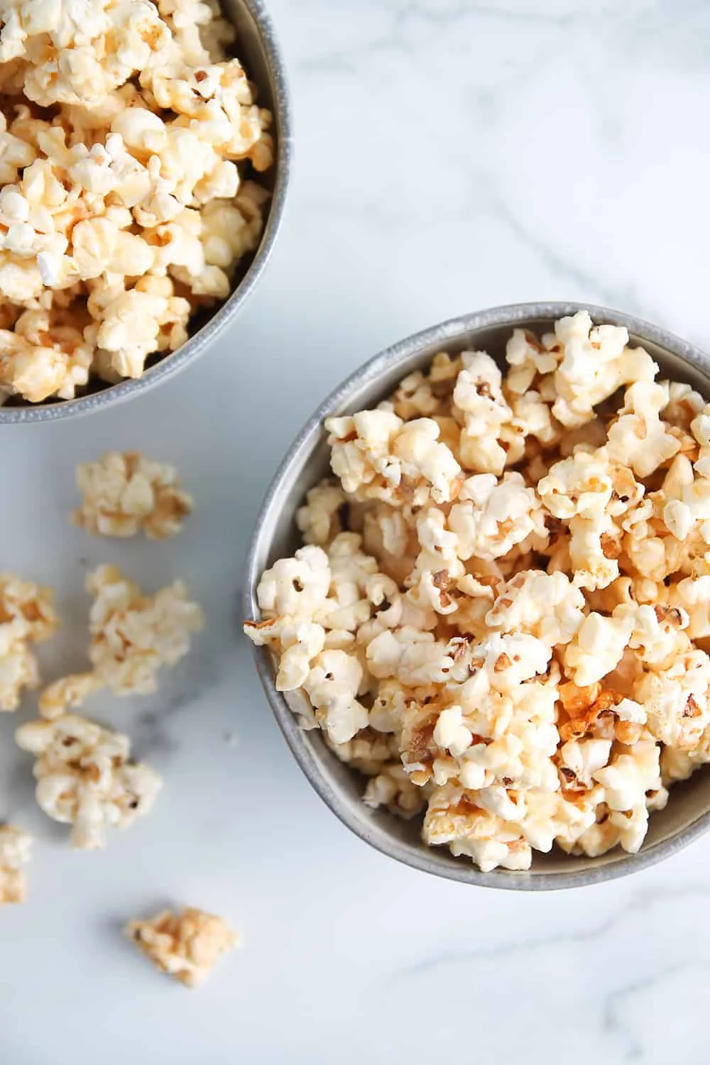 Overhead shot of microwave caramel corn in gray bowls on a marble surface