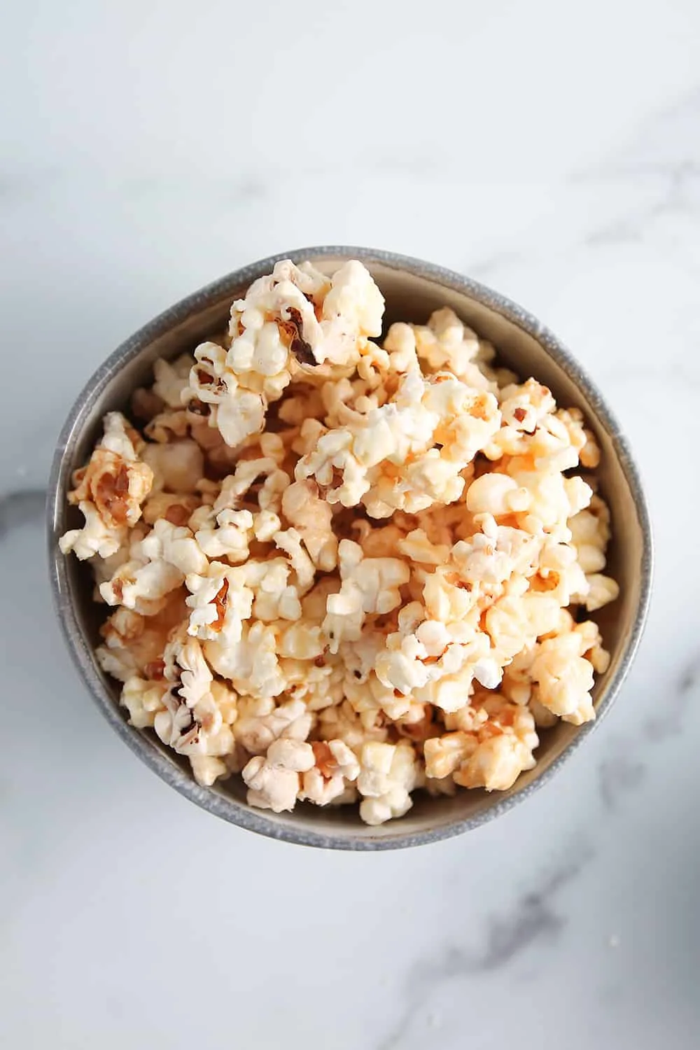 Bowl of microwave caramel popcorn on a marble surface