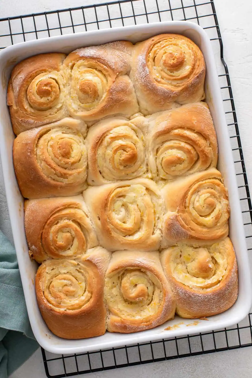 Baked orange rolls in a white baking dish set on a wire rack.