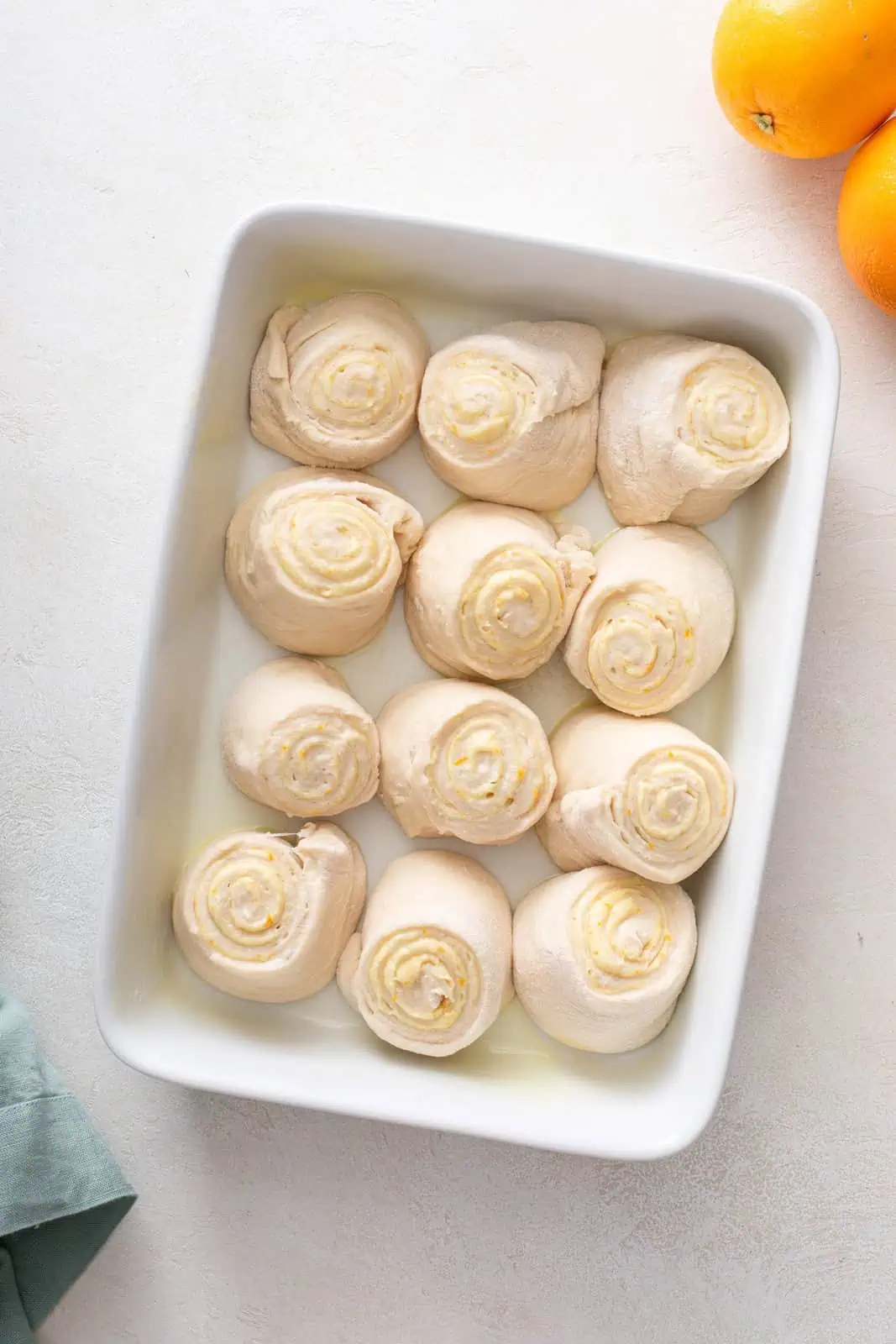 Sliced orange rolls set in a white baking dish, ready to be proofed.