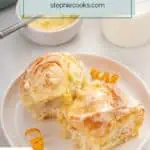 Two frosted orange rolls arranged on a white plate. Text overlay includes recipe name.