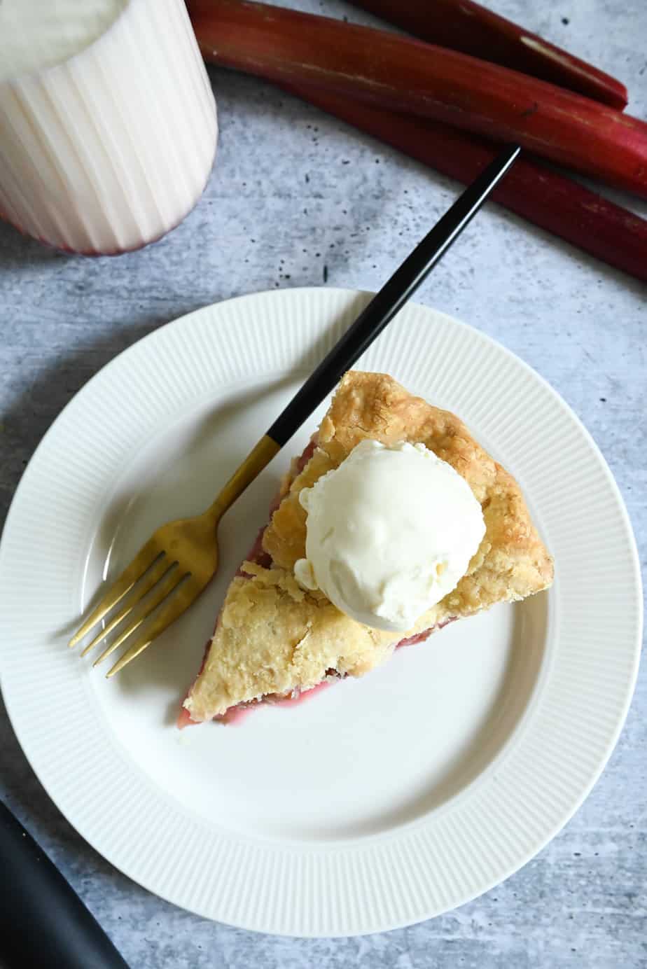 Overhead view of a slice of rhubarb pie with a scoop of vanilla ice cream on top.