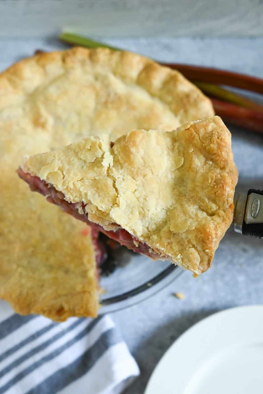 Pie server holding up a slice of rhubarb pie from the pie plate.