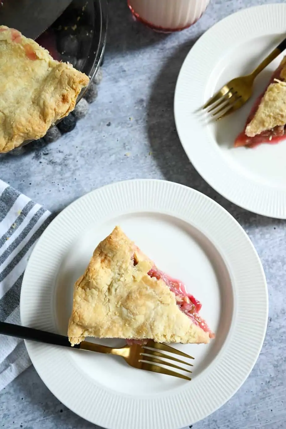 Overhead view of two white plates with slices of rhubarb pie on them.