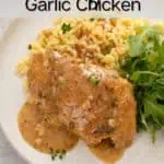 Close up of a garlic chicken thigh topped with sauce and plated next to orzo and an arugula salad. Text overlay includes recipe name.