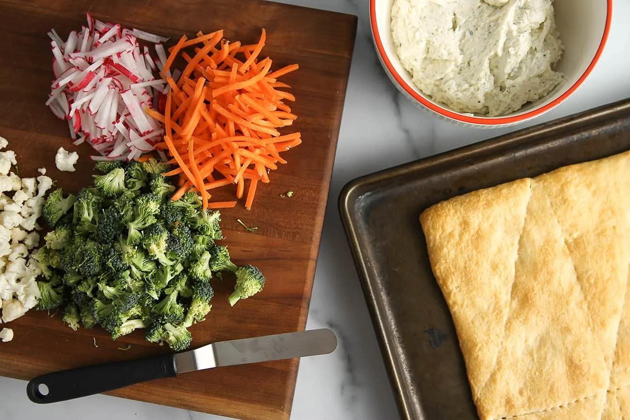 Top crescent roll dough with ranch cream cheese and raw veggies to make Vegetable Pizza