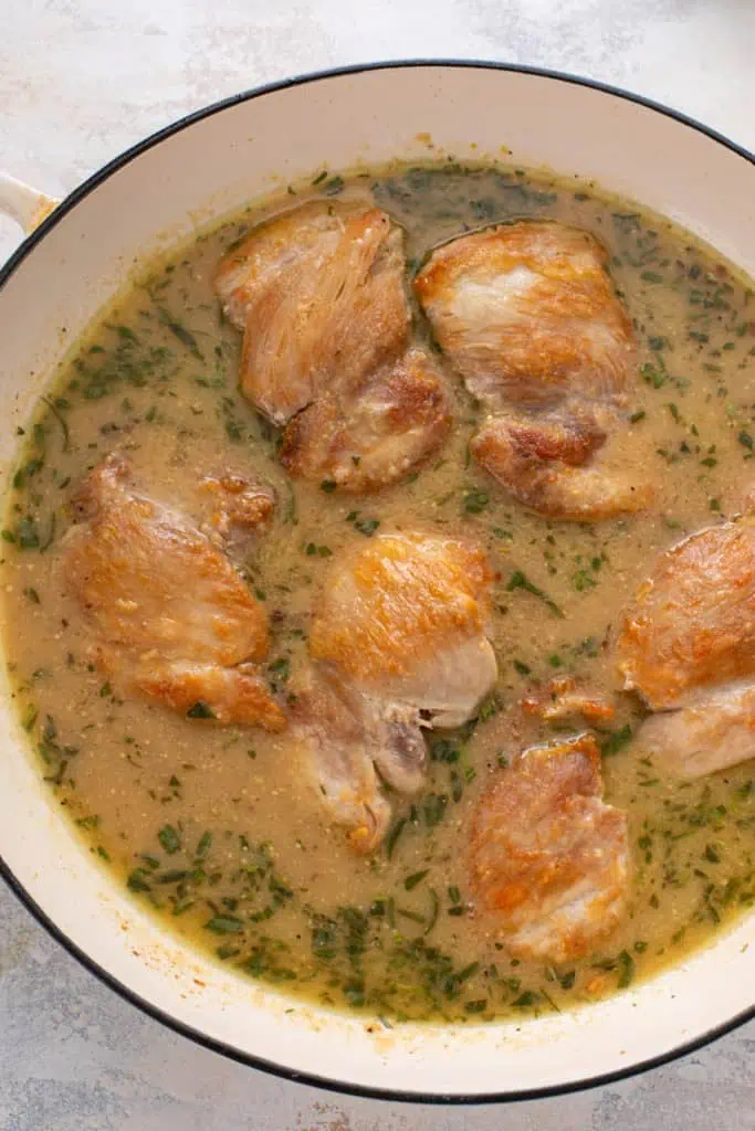 Seared chicken thighs added into sauce in a skillet, ready to finish cooking in the oven.