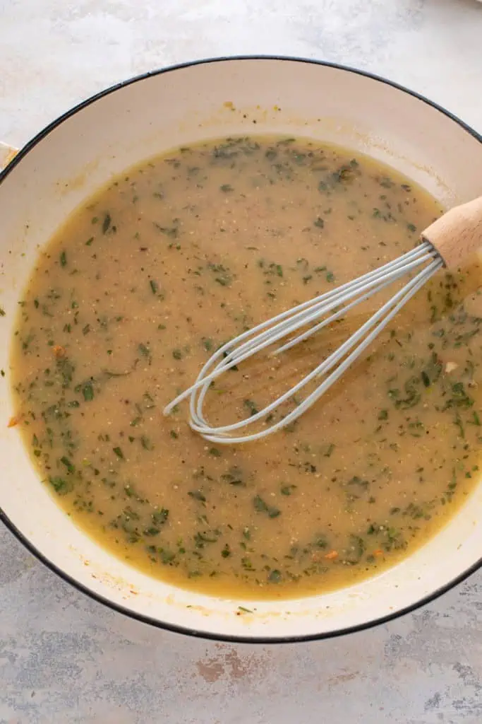 Sauce for garlic chicken being whisked in a skillet.