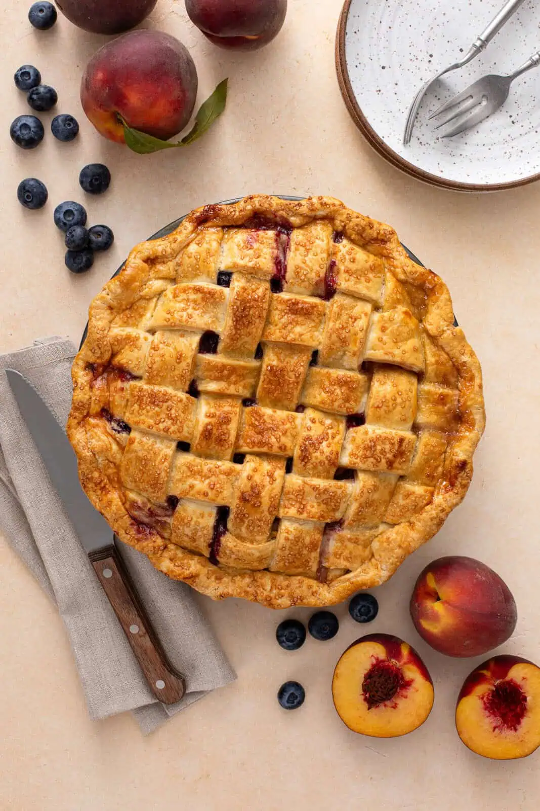 Overhead view of a cooled peach blueberry pie topped with a lattice crust on a countertop.