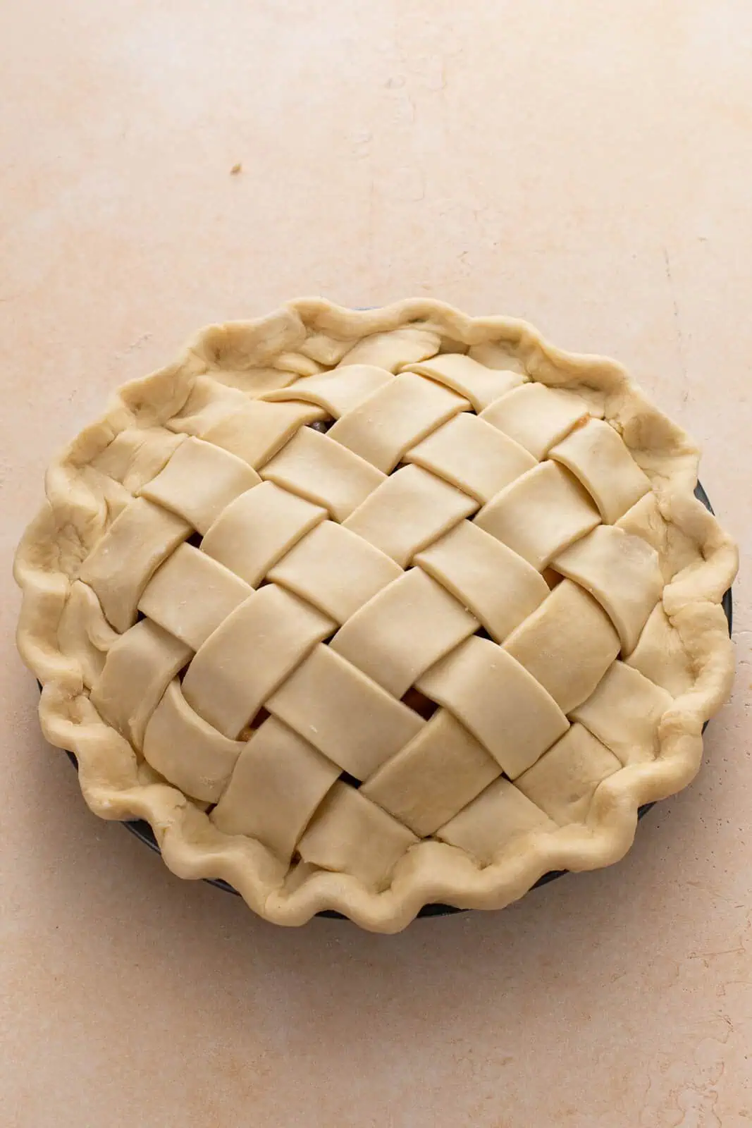 Unbaked pie topped in a lattice crust with the edged trimmed and crimped.