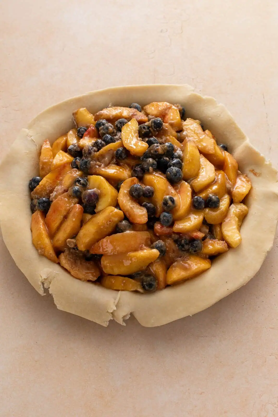 Peach blueberry pie filling added to a pie crust.
