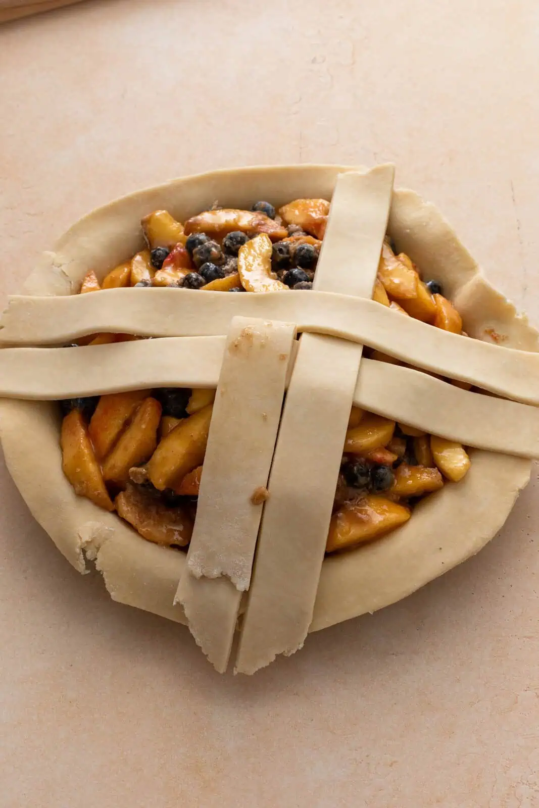 Four strips of pie dough being woven to start a lattice crust.