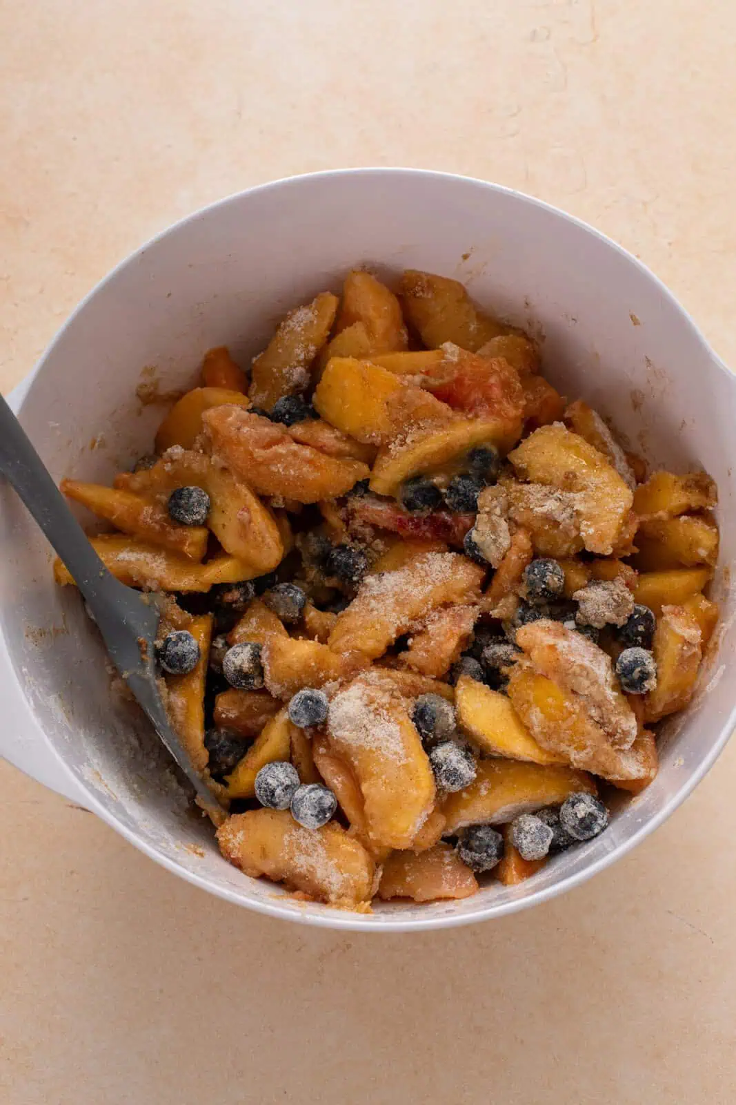 Filling for peach blueberry pie stirred in a large bowl.
