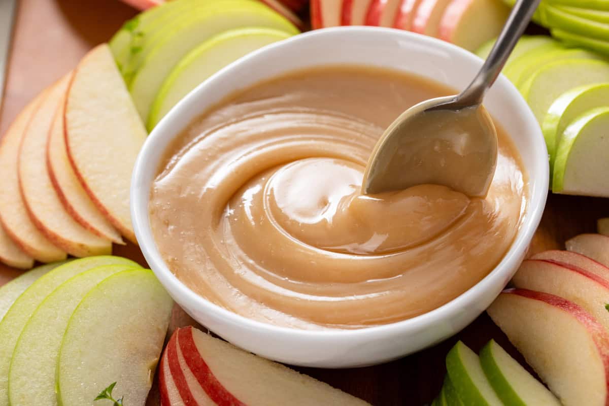 Spoon stirring easy apple dip in a white bowl.