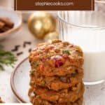 Four fruitcake cookies stacked on a plate in front of a glass of milk. Text overlay includes recipe name.