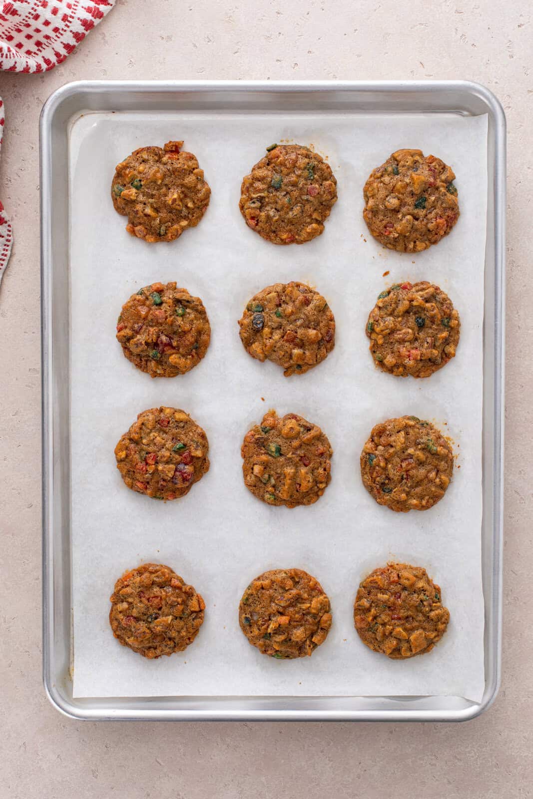 Baked fruitcake cookies resting on a baking sheet.