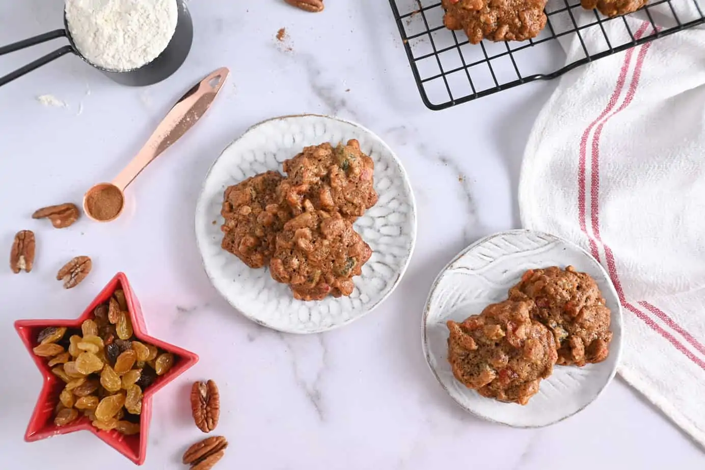 Two white ceramic plates with fruitcake cookies on them.