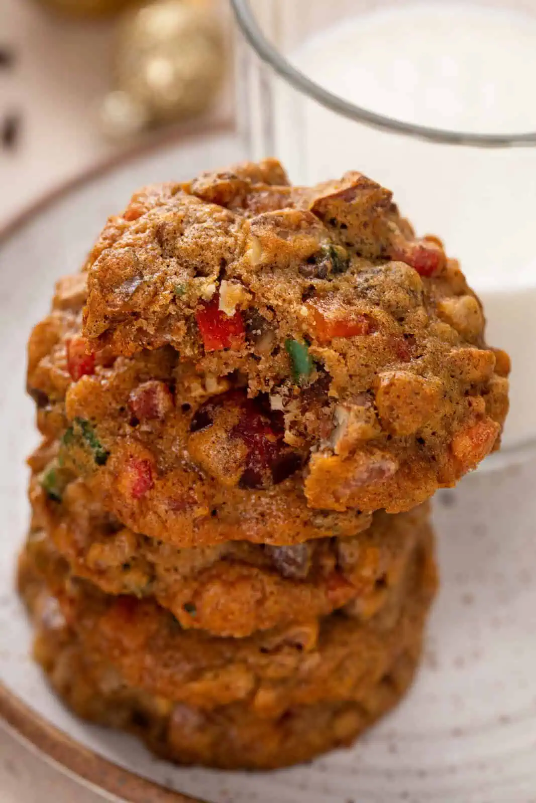 Stacked fruitcake cookies on a plate, with a bite taken from the top cookie.