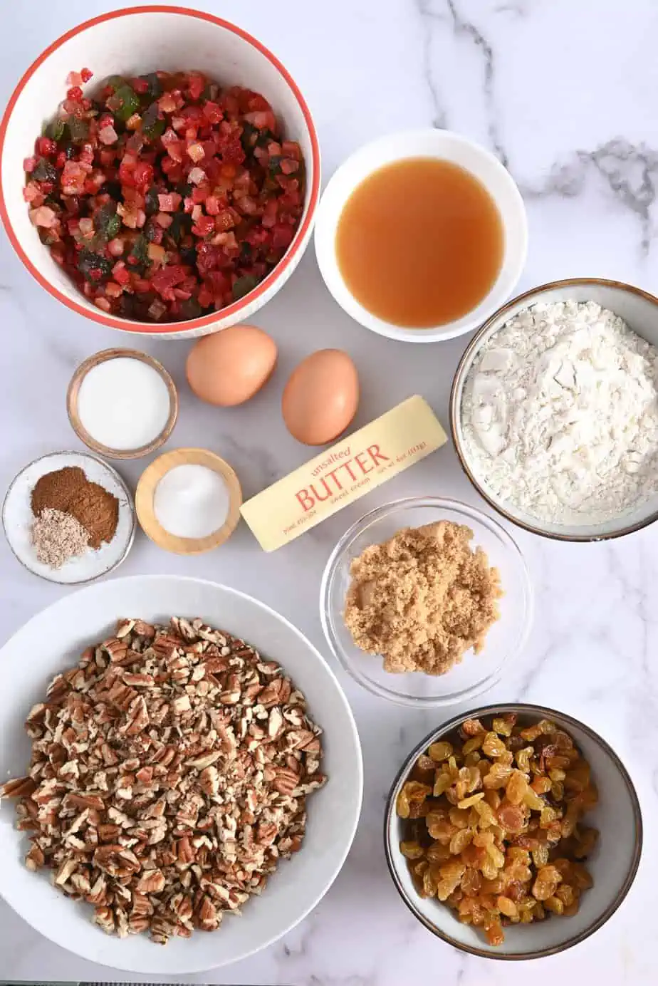 Fruitcake cookie ingredients arranged on a marble countertop.