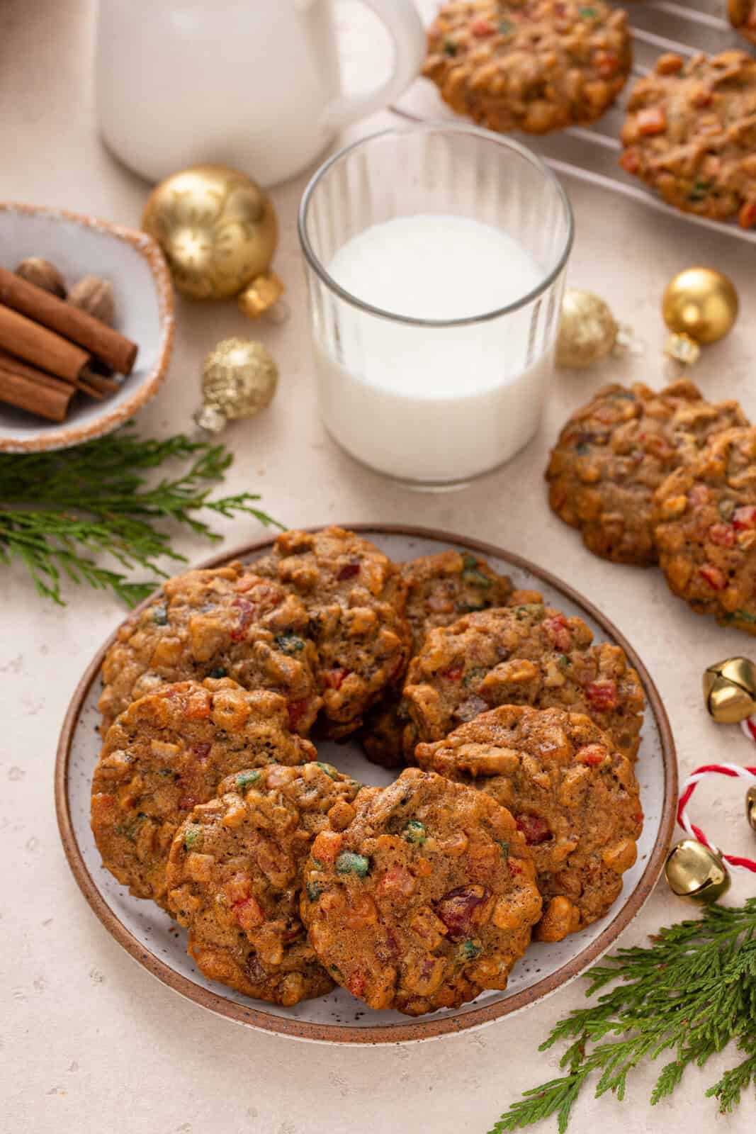 Fruitcake cookies arranged in a circle on a plate. A glass of milk is in the background.