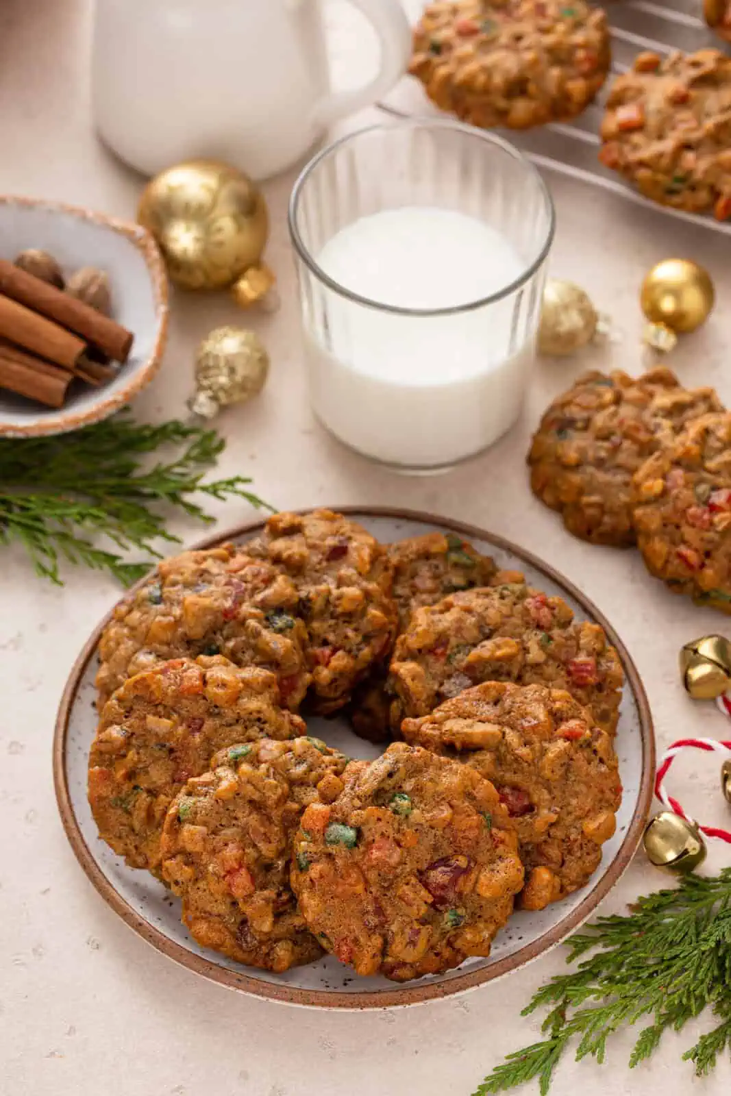 Fruitcake cookies arranged in a circle on a plate. A glass of milk is in the background.