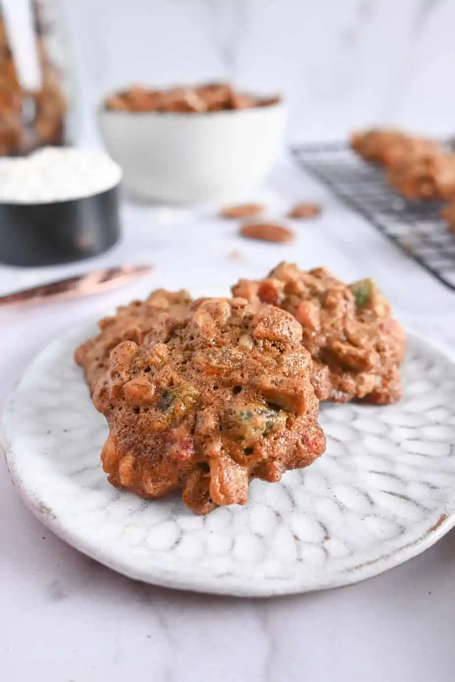 Three fruitcake cookies arranged on a white ceramic plate.