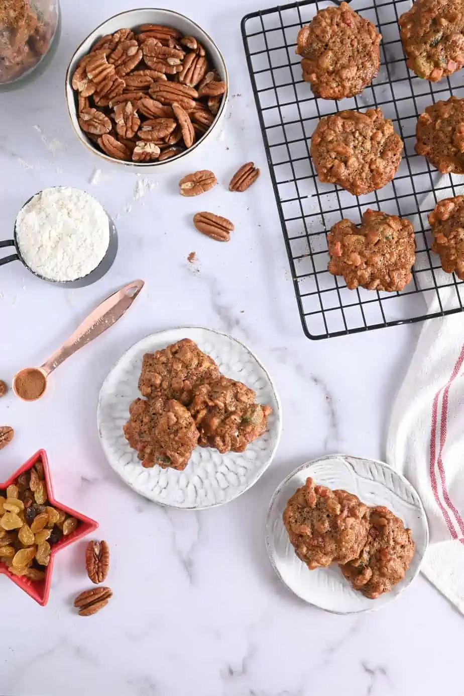 Fruitcake cookies arranged on white ceramic plates and metal cooling rack.