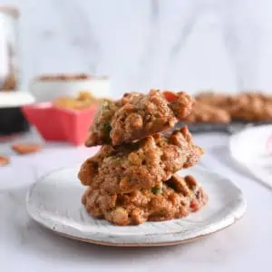 Three fruitcake cookies stacked on a white plate.