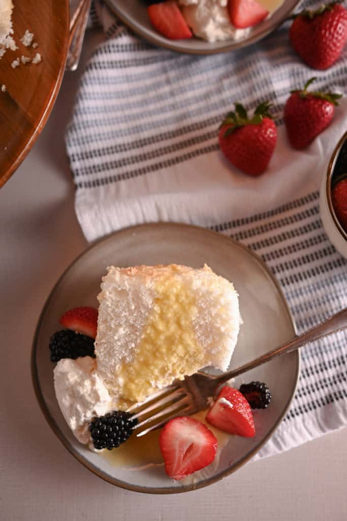 Slice of angel food cake with a bite taken out of it. A fork is set on the plate next to the cake