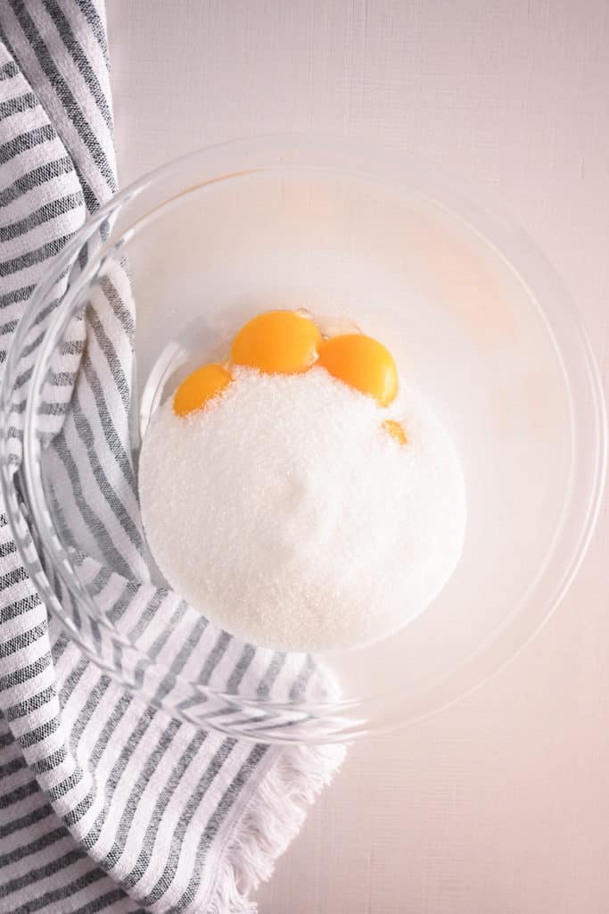Egg yolks and sugar in a glass mixing bowl