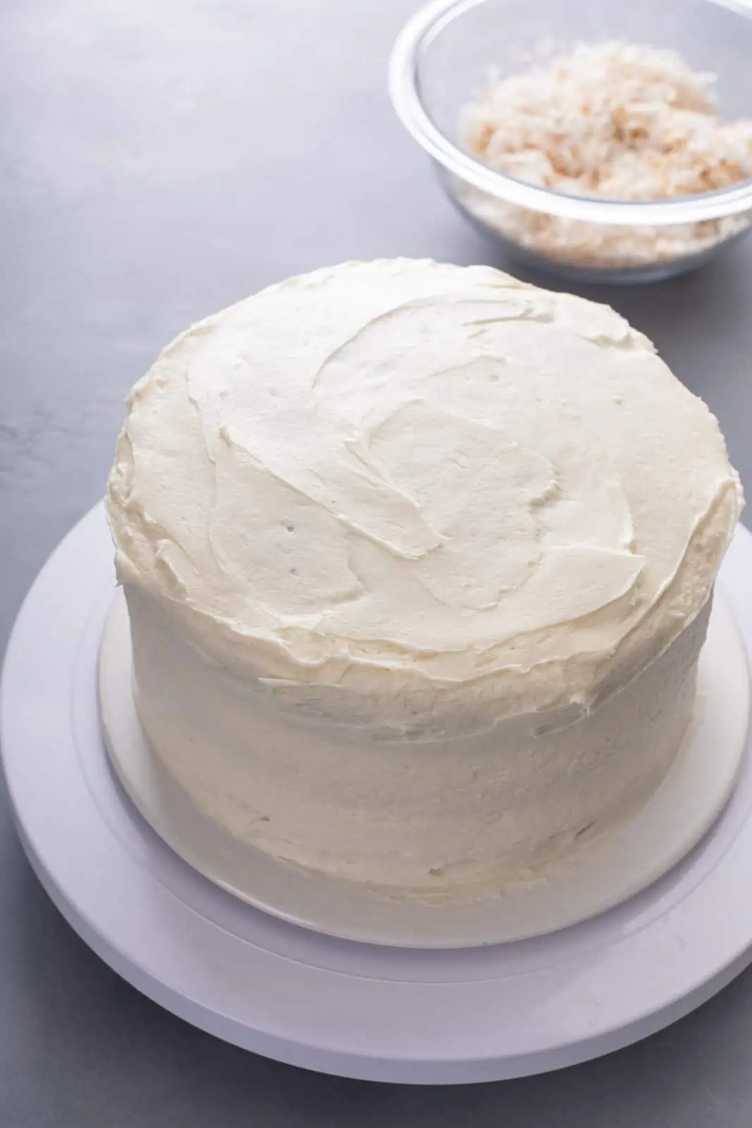 Coconut cake covered in white frosting.