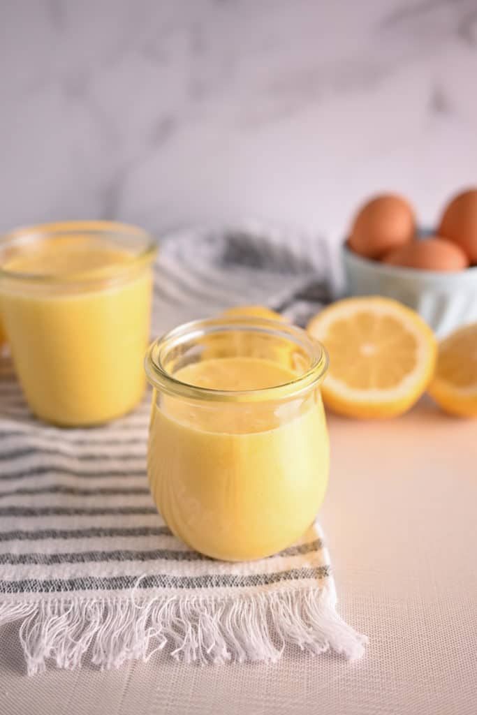 Jar of lemon curd set on a striped towel with a second jar in the background