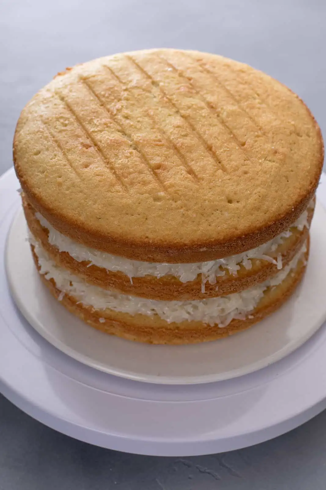 Layers of coconut cake stacked with coconut filling.