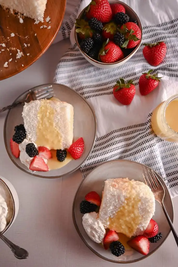 Two plated slices of angel food cake, each topped with lemon curd and fresh berries