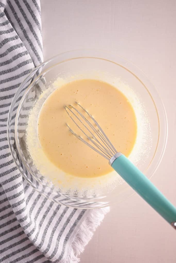 Ingredients for lemon curd whisked together in a glass bowl